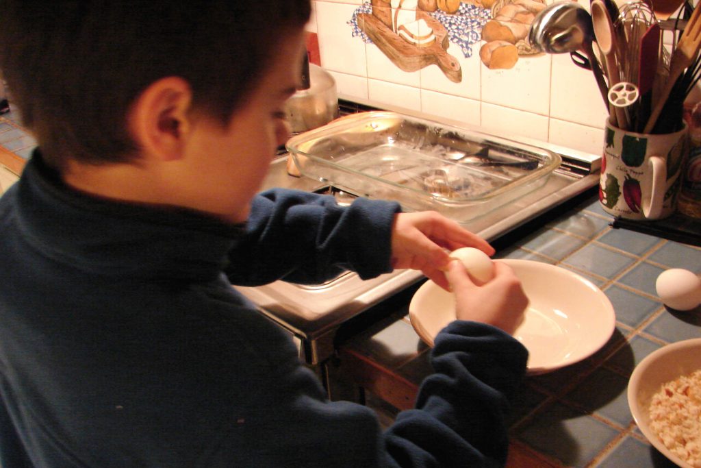 Boy cracks eggs into bowl