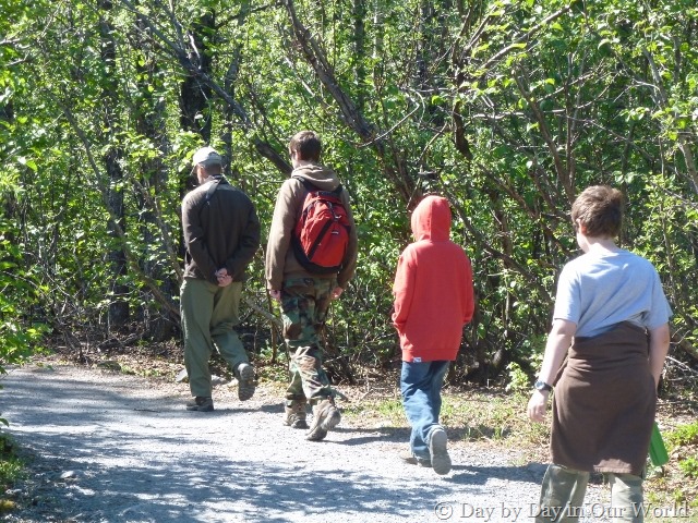 Man and three boys walk down a trail.