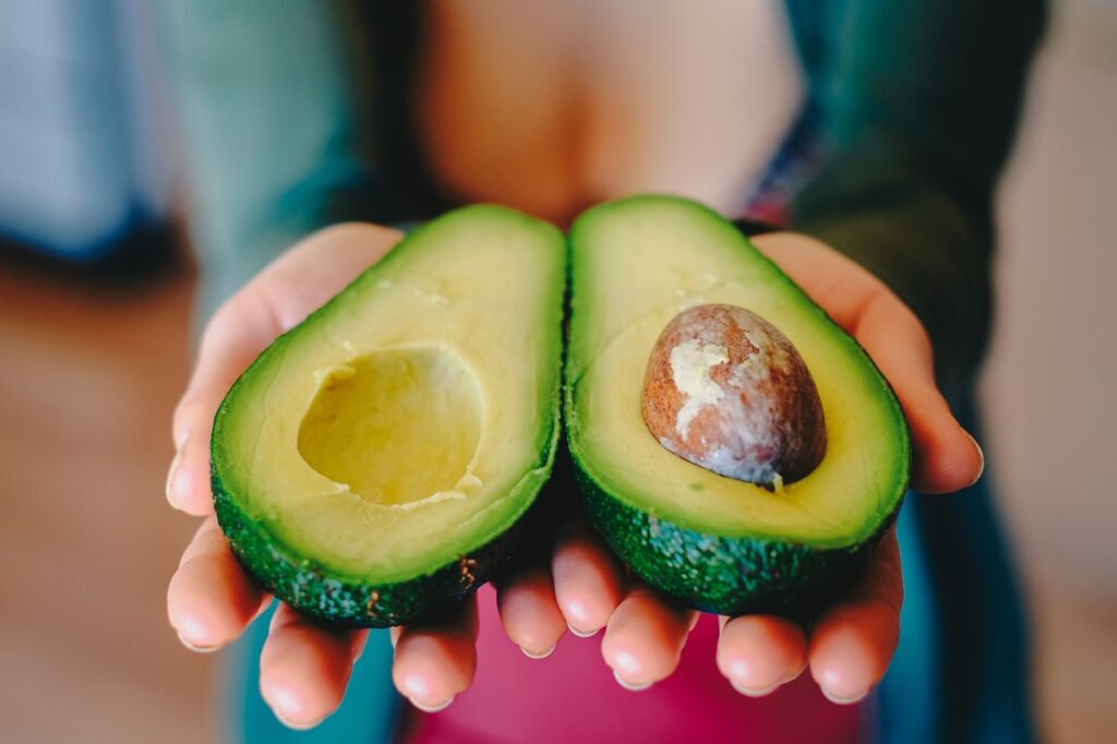 avocado halves held in palm of hands.