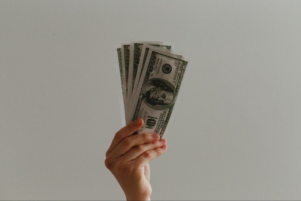 holding stack of $100 bills in the air