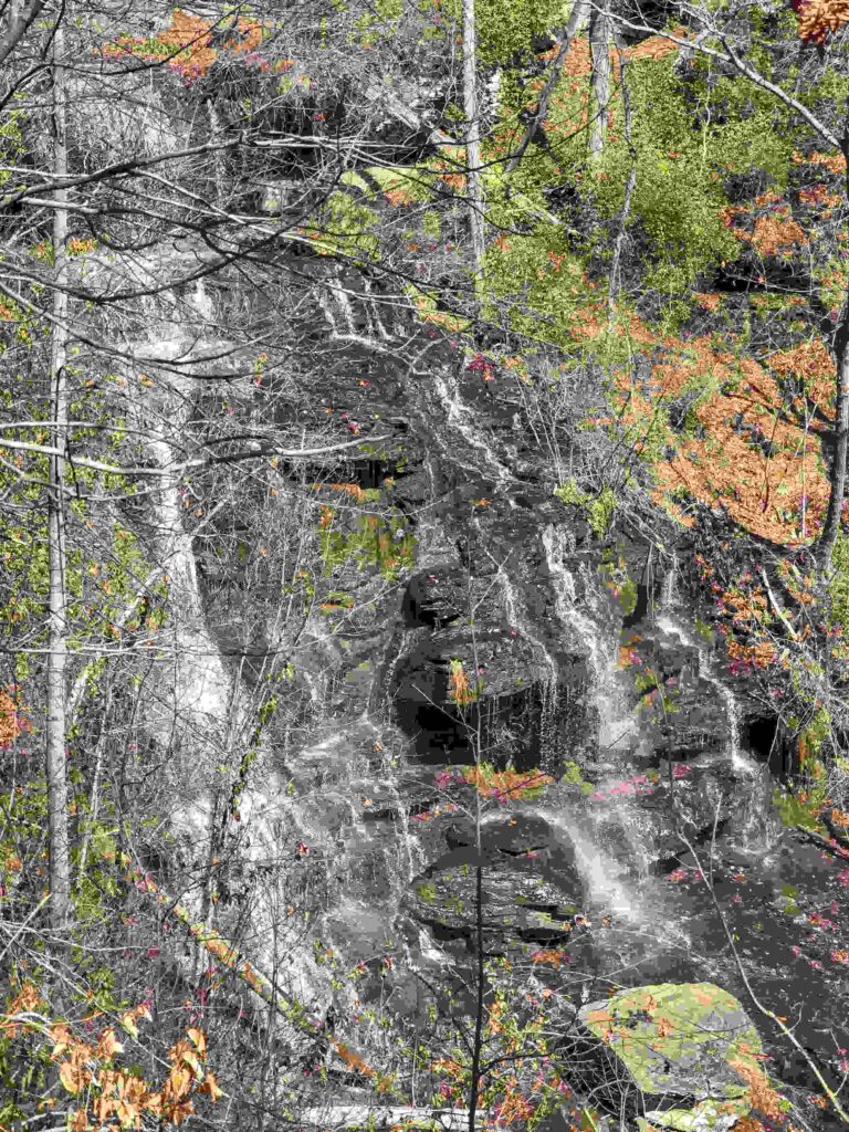 Rocky hillside with waterfall and trees.