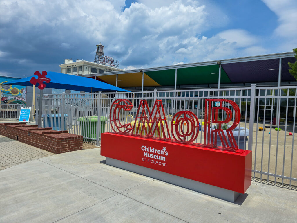 Colorful entrance to the Children’s Museum of Richmond with a large red CMoR sign beneath a blue sky.