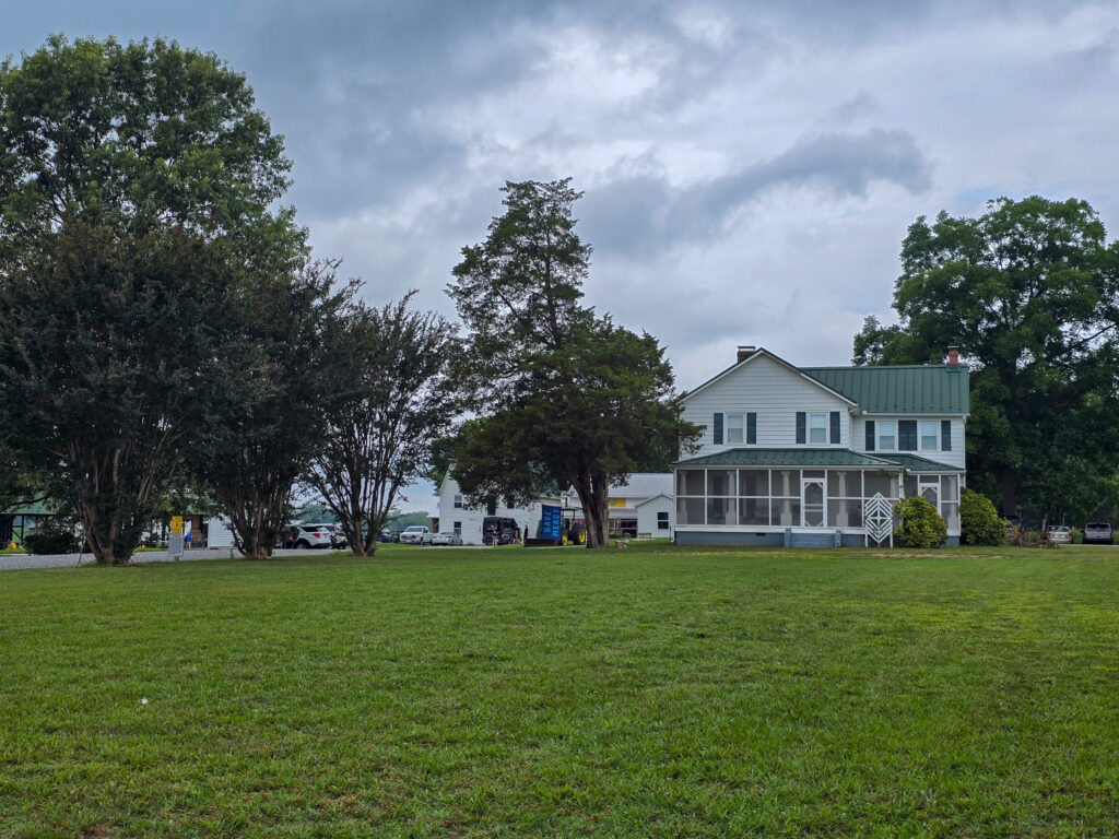 White farmhouse and surrounding green lawn at Old Tavern Farm outside Richmond, Virginia, beneath an overcast sky.